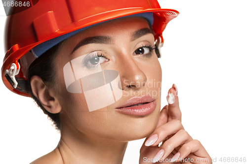 Image of Portrait of confident female worker in orange helmet