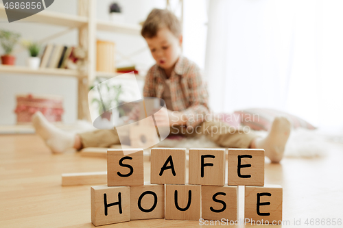 Image of Wooden cubes with words SAFE HOUSE in hands of little boy