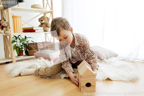 Image of Little child sitting on the floor. Pretty boy palying with wooden cubes at home