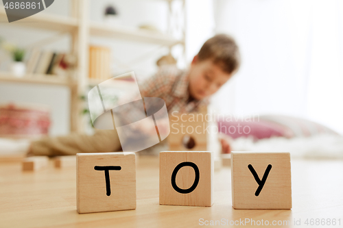 Image of Wooden cubes with word TOY in hands of little boy