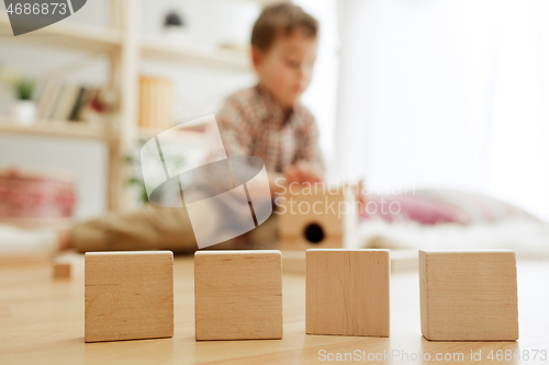 Image of Little child sitting on the floor. Pretty boy palying with wooden cubes at home