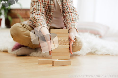 Image of Little child sitting on the floor. Pretty boy palying with wooden cubes at home