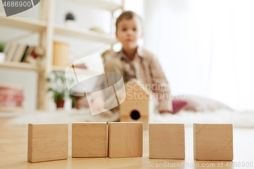 Image of Little child sitting on the floor. Pretty boy palying with wooden cubes at home