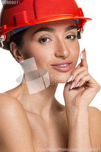 Image of Portrait of confident female worker in orange helmet