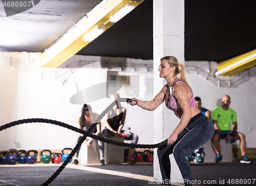 Image of athlete woman doing battle ropes cross fitness exercise