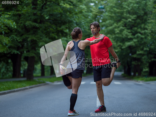 Image of runners team warming up and stretching before morning training