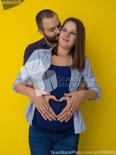 Image of pregnant couple  isolated over yellow background