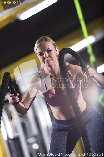 Image of athlete woman doing battle ropes cross fitness exercise