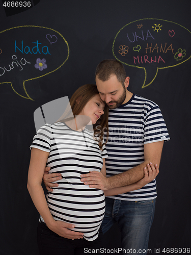 Image of pregnant couple posing against black chalk drawing board