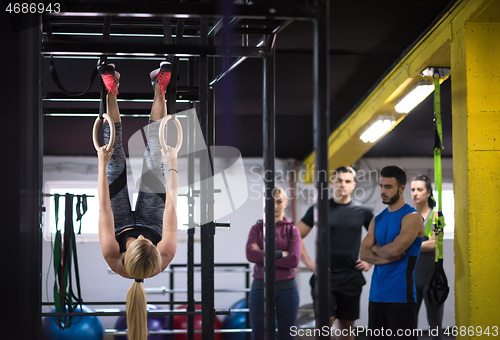 Image of woman working out with personal trainer on gymnastic rings