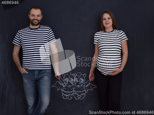 Image of pregnant couple drawing their imaginations on chalk board