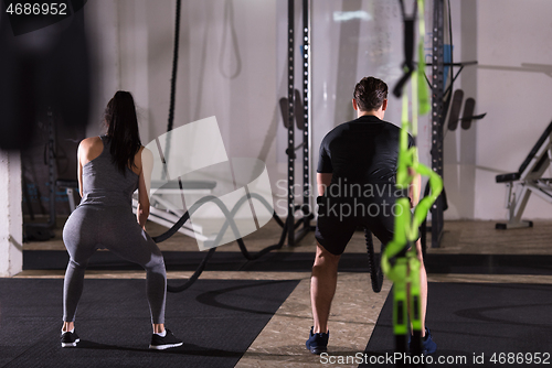 Image of sports couple doing battle ropes cross fitness exercise