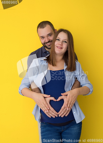 Image of pregnant couple  isolated over yellow background