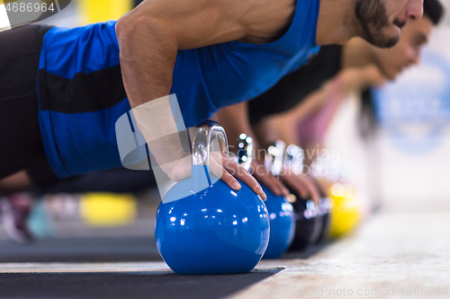 Image of young athletes doing pushups with kettlebells