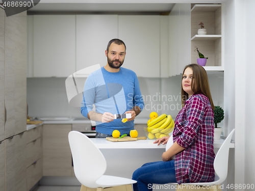 Image of couple cooking food fruit lemon juice at kitchen