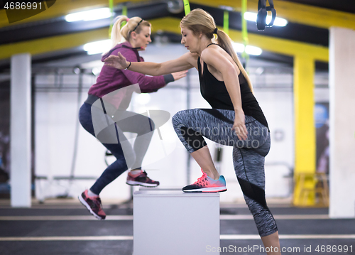 Image of athletes working out  jumping on fit box