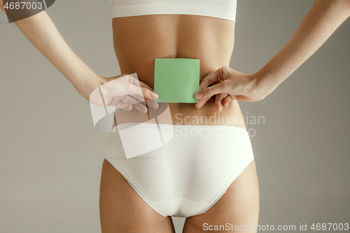 Image of Beautiful young body. Naked back of a woman, isolated on gray background.