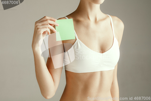 Image of Young adult woman holding empty paper card for sign or symbol.