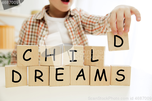 Image of Wooden cubes with words CHILD DREAMS in hands of little boy