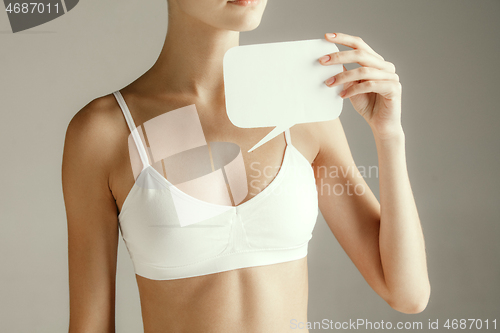 Image of Young adult woman holding empty paper card for sign or symbol.