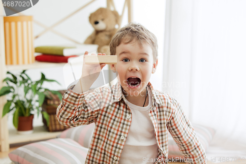 Image of Little child sitting on the floor. Pretty boy palying with wooden cubes at home