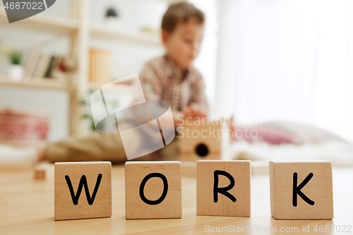 Image of Wooden cubes with word WORK in hands of little boy