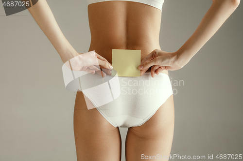 Image of Beautiful young body. Naked back of a woman, isolated on gray background.