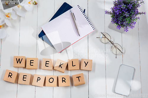 Image of WEEKLY REPORT. Message at wooden cubes on a desk background.