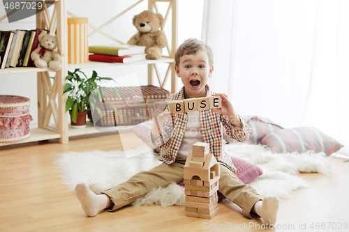 Image of Wooden cubes with word ABUSE in hands of little boy