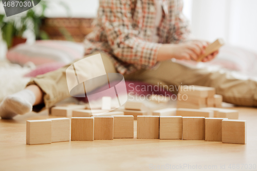 Image of Little child sitting on the floor. Pretty boy palying with wooden cubes at home