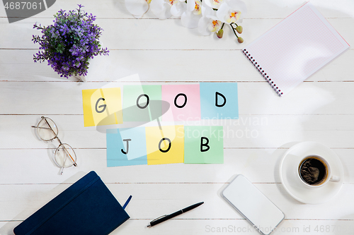 Image of GOOD JOB. Message at colorful note papers on a desk background.