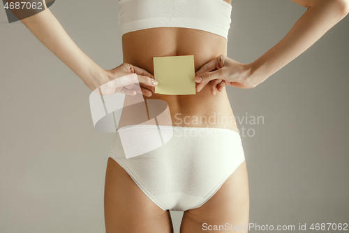 Image of Beautiful young body. Naked back of a woman, isolated on gray background.