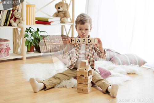 Image of Wooden cubes with word HARD in hands of little boy