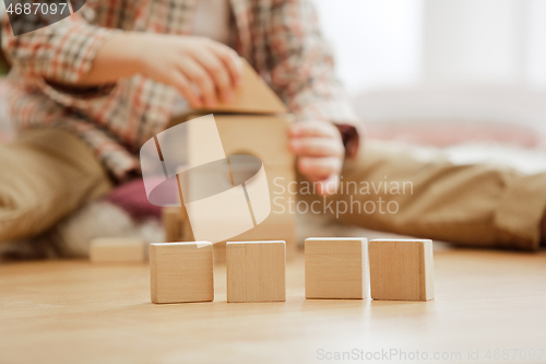 Image of Little child sitting on the floor. Pretty boy palying with wooden cubes at home