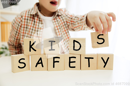 Image of Wooden cubes with words KIDS SAFETY in hands of little boy