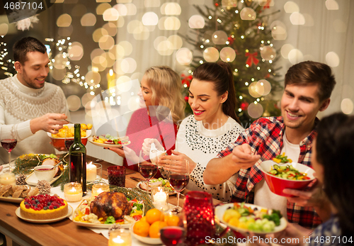 Image of happy friends having christmas dinner at home