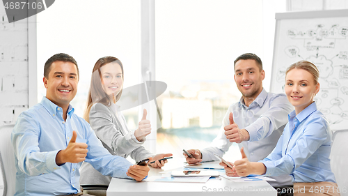 Image of happy business team showing thumbs up at office