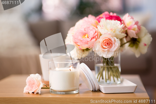 Image of burning candle and flower bunch on wooden table