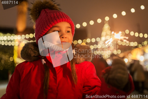 Image of happy girl with sparkler at christmas market