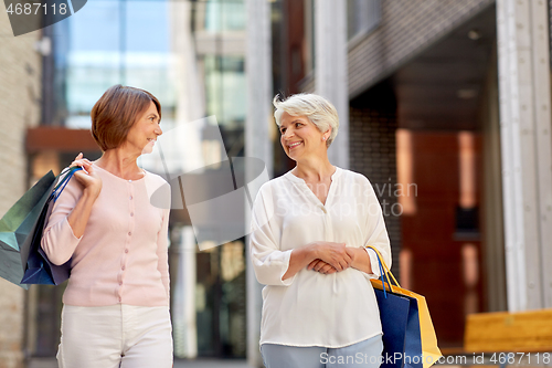 Image of senior women with shopping bags walking in city