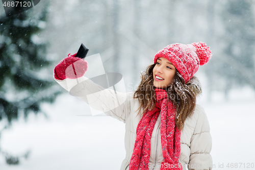 Image of young woman taking selfie by smartphone in winter