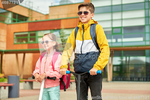 Image of happy school children with backpacks and scooters