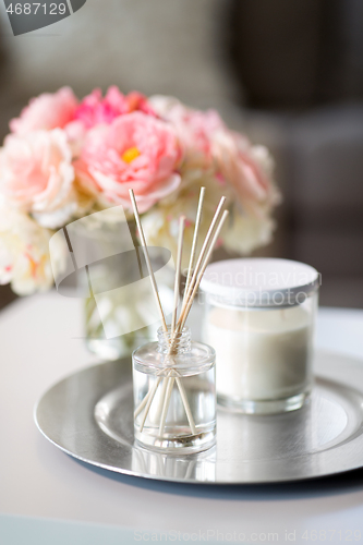 Image of aroma reed diffuser, candle and flowers on table