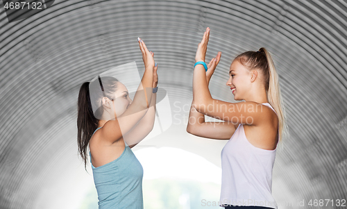 Image of happy women with fitness trackers making high five