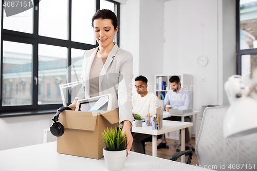 Image of happy businesswoman with personal stuff at office