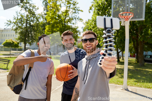 Image of happy men taking selfie on basketball playground