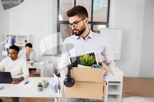 Image of sad fired male office worker with personal stuff