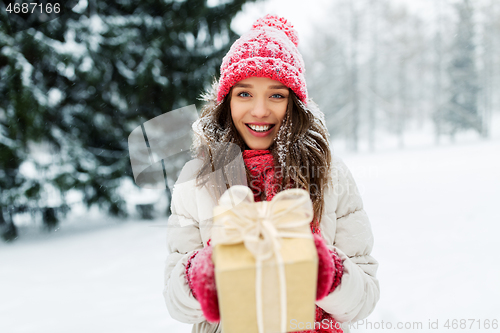 Image of happy young woman with christmas gift in winter