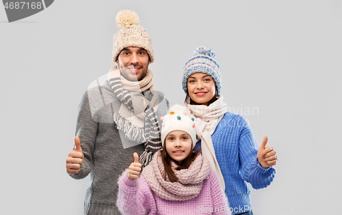 Image of happy family in winter clothes on grey background