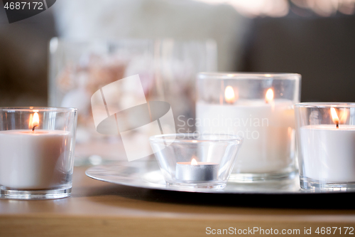 Image of burning white fragrance candles on tray on table